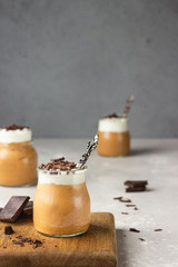 Chocolate mousse with whipped cream and pieces of chocolate in portion glasses, light grey...