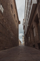 Narrow empty street in Santiago de Compostela, Spain. Road between ancient stone buildings. Medieval architecture. Travel concept. Old town district. Stone houses in european town. 