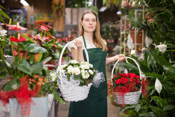 Portrait of woman florist with baskets of flowers in flower shop