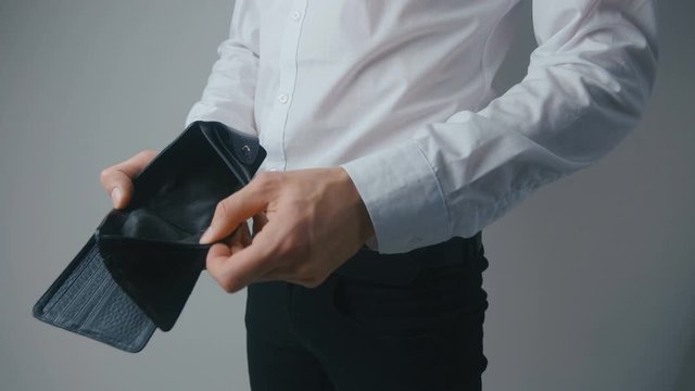 Close-up of a man's hand holding Leather Wallet Empty with No Money. The concept of poverty. Businessman in white shirt busted bankrupt.