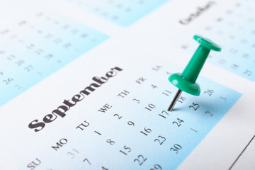 Calendar page marked with drawing pin, closeup