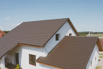 Fototapeta na wymiar Brown metal tile on the roof of the house. Corrugated metal roof