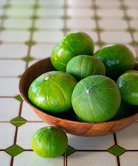 Wooden bowl filled with fresh zucchini on ceramic table