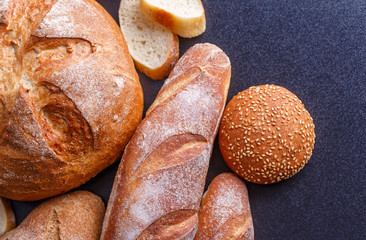 Bakery - gold rustic crusty loaves of bread and buns on black chalkboard background.