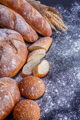 Bakery - gold rustic crusty loaves of bread and buns on black chalkboard background.