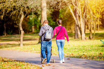 Fototapeta premium A married couple rolls a baby stroller in a city Park