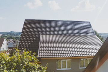 Brown metal tile on the roof of the house. Corrugated metal roof