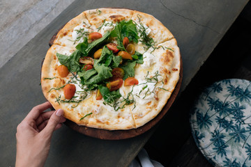 Female hand take a piece of Fresh italian pizza with tomatoes, cheese, basil on black stone table. Copy space. Homemade with love. Fast delivery. Recipe and menu. Top view.