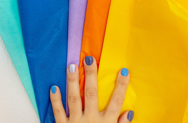 Samples of multi-colored wrapping paper in a female hand with manicure. Paper Coloring Examples