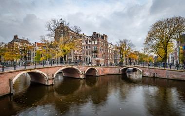Naklejka premium Night view of Amterdam cityscape with canal, bridge and medieval houses in the evening twilight illuminated. Amsterdam, Netherlands