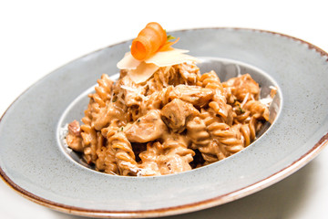 Homemade pasta with chicken, cheese and piece of carrot in a rustic plate