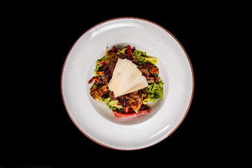 Meal made of green salad,  fresh chicken, crispy bacon nad cheese on top