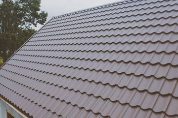 Brown metal tile on the roof of the house. Corrugated metal roof