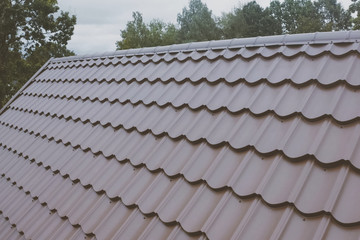 Brown metal tile on the roof of the house. Corrugated metal roof