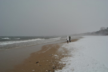 People are walking alond the Baltic sea at winter time. 