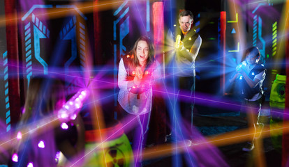 Parents and children playing laser tag in beams - obrazy, fototapety, plakaty