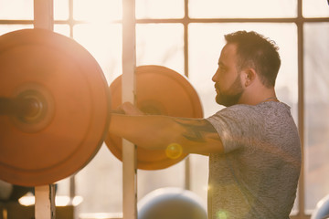 Man ready to squat with barbell in a fitness gym making his muscles more strong