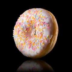 Glazed donut with reflection on a black background rotated in three quarters