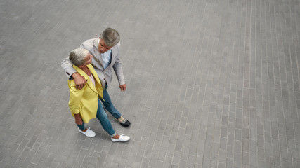 Spending time together. Top view of stylish mature couple hugging and walking together through the city street