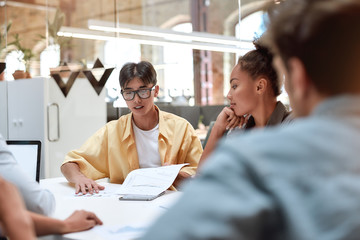Project team. Young asian man discussing something with his young colleagues while working together in the modern office