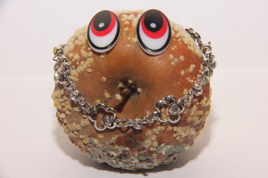 Apple covered with rot with eyes in the image of a man with expensive jewelry