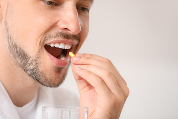 Doctor taking pill on light background, closeup