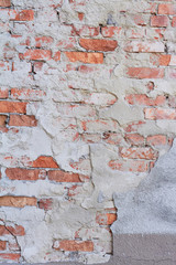 Old weathered red brick wall fragment, crumbling plaster