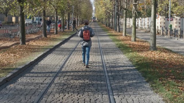 Paving of Europe. Girl tourist walks along the paving stones on the tram tracks in old Europe.