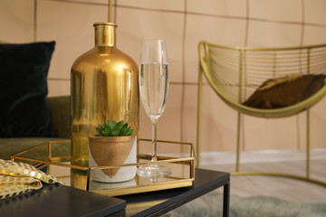 Tray with vase, plant and glass of champagne on table