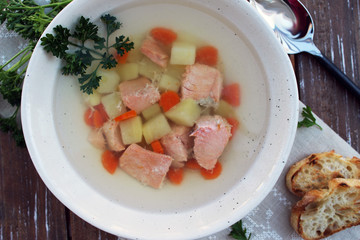 Salmon soup with potatoes and carrot on the wooden background