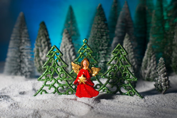 Little white guardian angel in snow. Festive background. Christmas decorations.