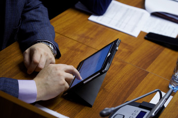 Man in a formal suit during a business meeting. Official, businessman or deputy uses the touch...