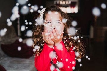 young girl blowing artificial snow flakes at home. Christmas concept