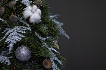 Christmas and New Year composition. Detail closeup Christmas tree made of fir branches and decorated by natural materials and balls on dark backdrop