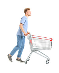 Young man with empty shopping cart on white background