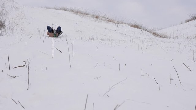happy childhood concept. child slides on sled from high snow hill during Christmas holidays in winter park. Slow motion