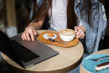 Hands of business woman wich sitting in a cafe. There's a laptop in front of her and cup of coffee. Business concept and co-working space. Horizontal