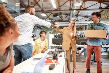 Nice to meet you. Young beautiful woman in suit giving fist bump to her new coworker while standing...