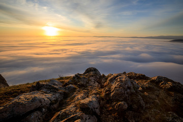 sunrise on a mountain peak with a lot of fog and clouds
