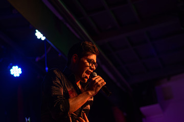 young man sings on stage performing a concert