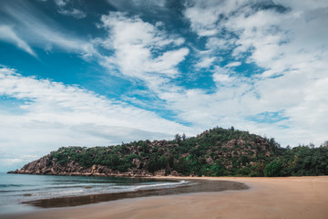 Sunny beach on Magnetic island, Australia with rocks and hills around