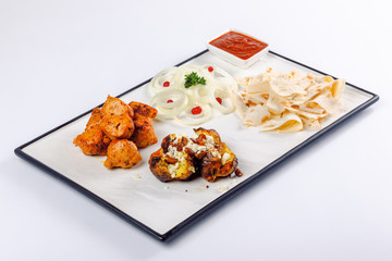 grilled chicken and baked potato with cheese. onion circles and pita bread, red sauce on a white board. great snack dish for beer