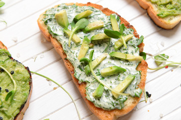 Tasty avocado sandwiches on white board, closeup