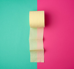 soft yellow toilet paper in a roll on a green-pink background