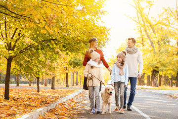 Happy family with dog walking in autumn park