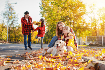Naklejka na ściany i meble Happy family with dog resting in autumn park