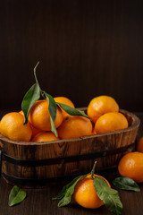 Old wooden box with fresh ripe mandarins on a dark table .  Dark background, with сopy space