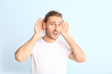Fototapeta premium Young man with hearing problem on light background