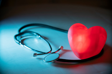 Red heart with stethoscope on blue background. Copy space