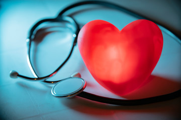 Red heart with stethoscope on blue background. Copy space